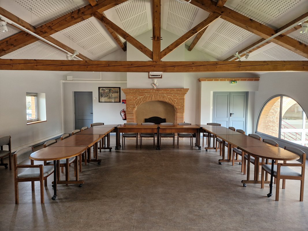 Grande pièce avec table disposées en U cheminée en pierre en fond